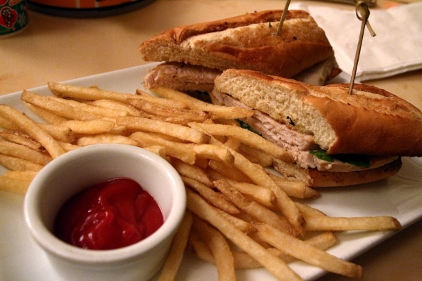 A sandwich and fries on a plate with a little cup of ketchup