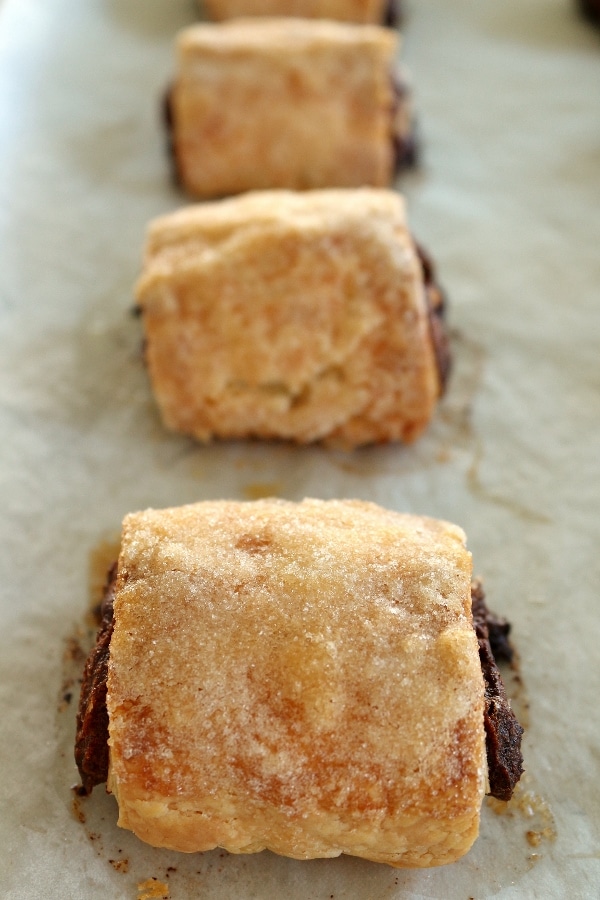 a row of date and chocolate rugelach on a parchment paper lined baking sheet