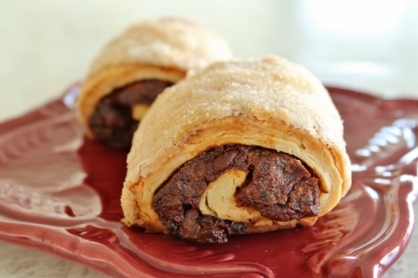 a side view of two date and chocolate rugelach pastries on a red plate