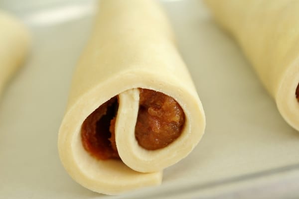 A closeup of an unbaked pastry roll filled with date paste