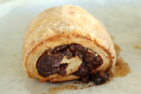 a closeup of a rugelach with date and chocolate filling peeking through the side
