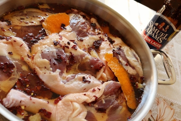 Duck legs with orange zest and seasonings in a large pot.