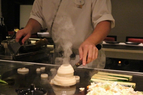 a chef\'s hands making a volcano out of onion slices