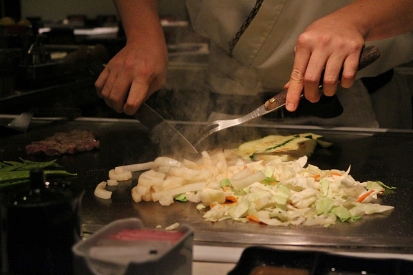 A chef cooking vegetables on a hot surface