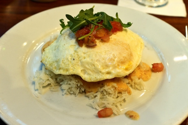 A plate of rice topped with a fried egg and chopped tomatoes