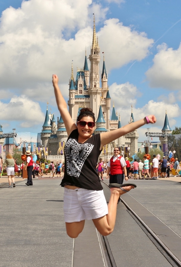 a woman jumping in the air in front of Cinderella\'s Castle at Disney\'s Magic Kingdom