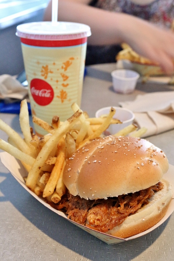 a pulled pork sandwich and fries in a paper basket