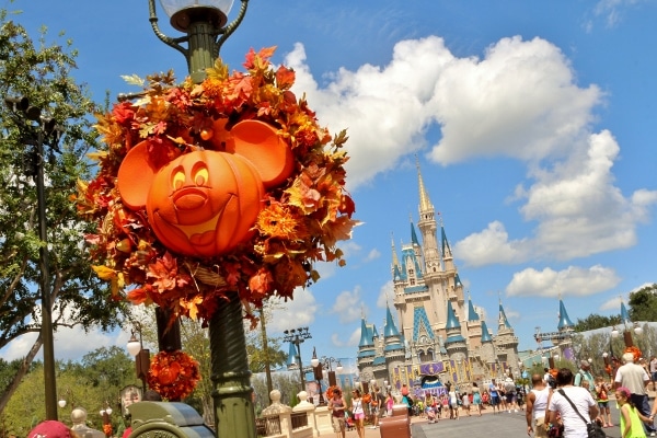 a pumpkin-shaped Mickey Mouse decoration on a light pole near Cinderella\'s Castle