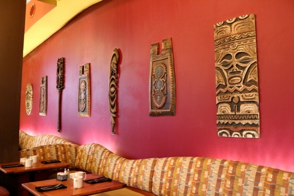 Polynesian themed wall hangings over a banquette bench