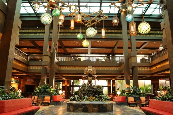 the lobby of Disney\'s Polynesian Village Resort with a tiki statue and colorful hanging lights