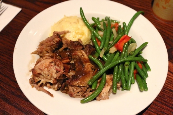 A plate of braised pork, mashed potatoes, and green beans