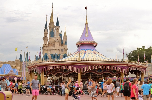 a covered carousel with Cinderella\'s Castle behind it