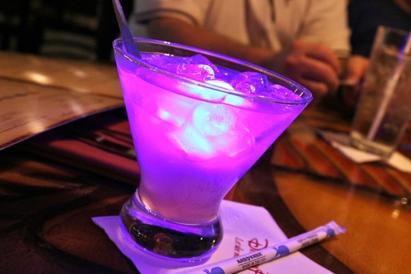 A colorful cocktail with a bright glow cube inside