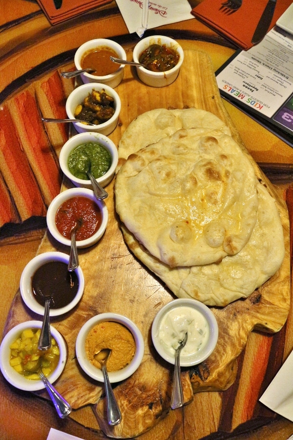 overhead view of a platter of naan surrounded by dipping sauces in little bowls