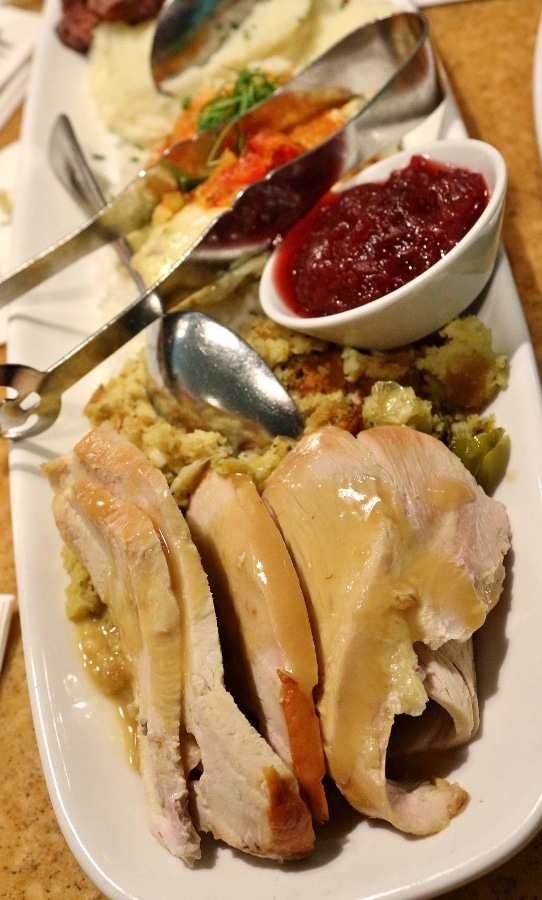 a closeup of roasted turkey with gravy on a long platter