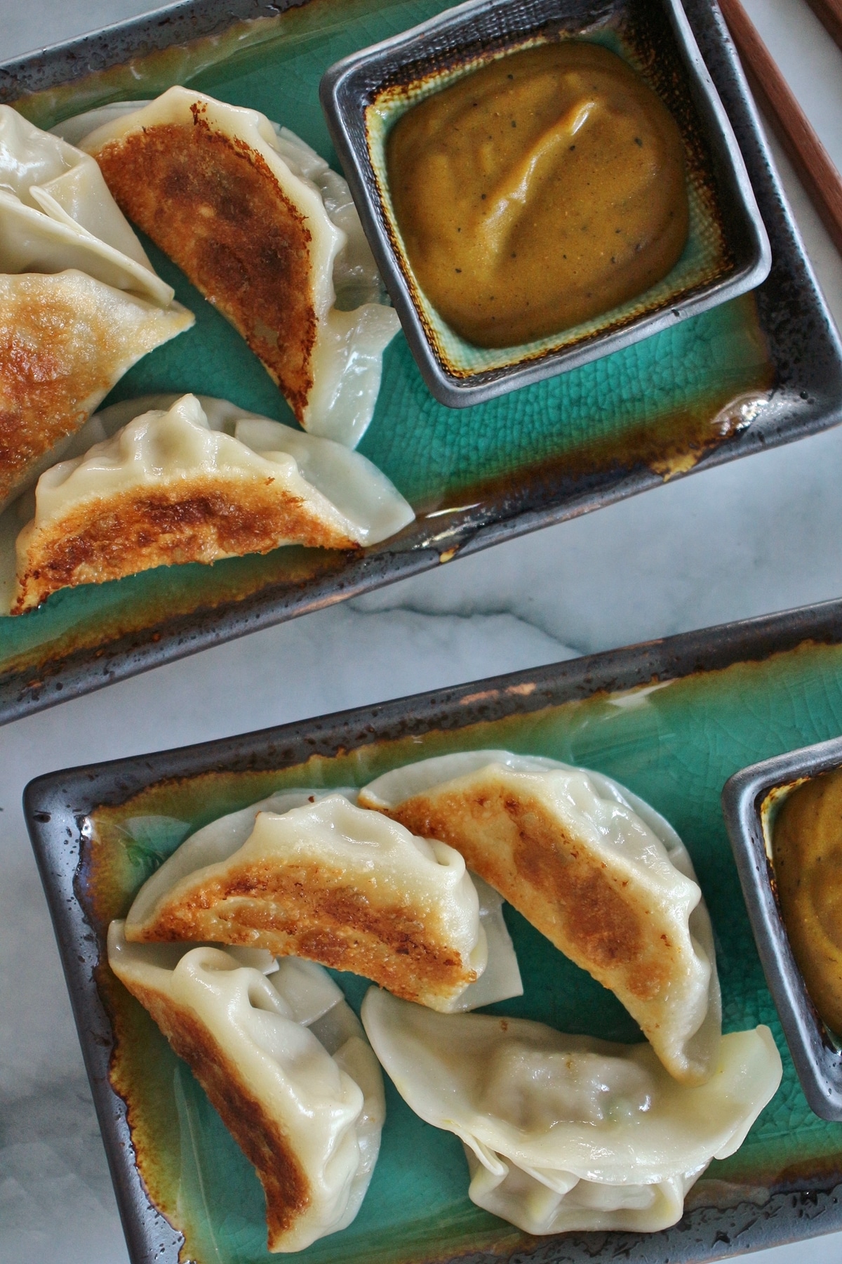 overhead view of 2 rectangular turquoise plates of pan-fried dumplings