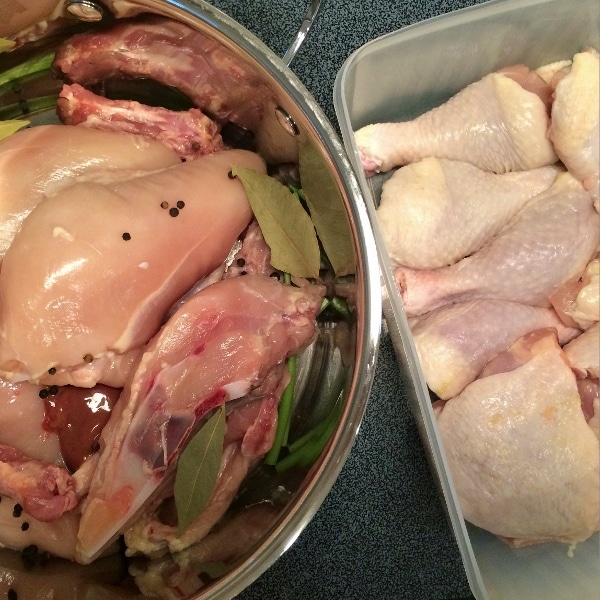 chicken pieces divided up between a stock pot and a tupperware dish