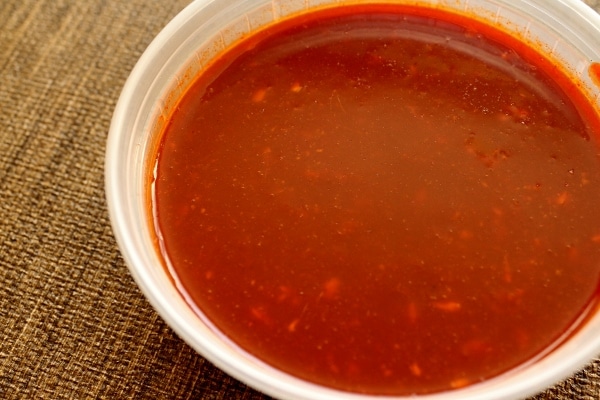 spicy red sauce for Korean fried chicken in a small plastic container