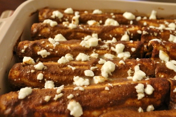 side view of a baking dish of enmoladas with crumbled white cheese on top