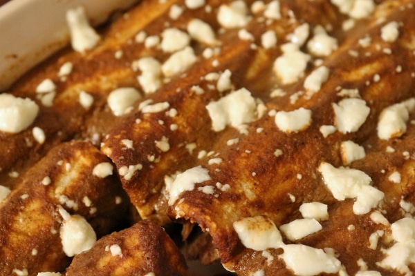 a closeup of baked enmoladas with crumbled white cheese on top