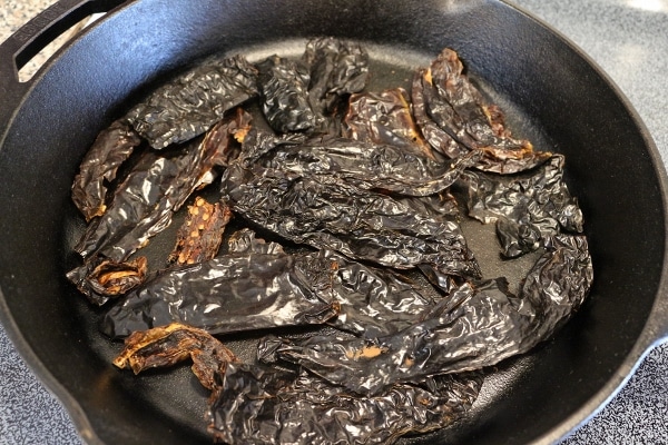 dried chiles toasting in a cast iron pan