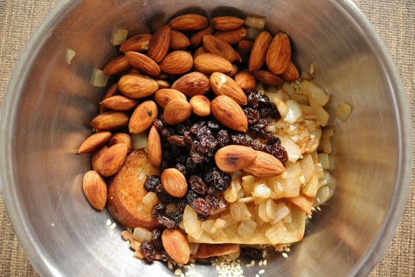 A bowl almonds, raisins, cooked onions, and other ingredients