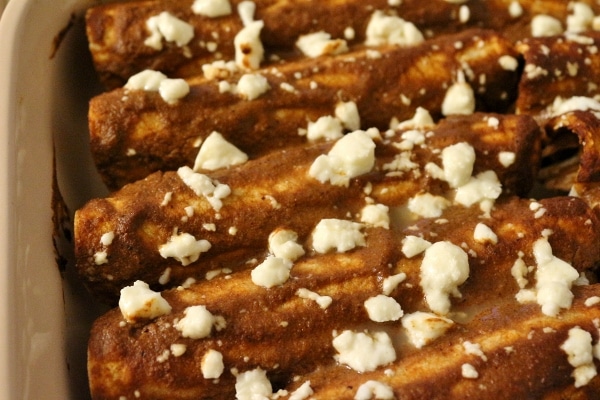 a closeup of baked chicken enchiladas with mole sauce and cheese