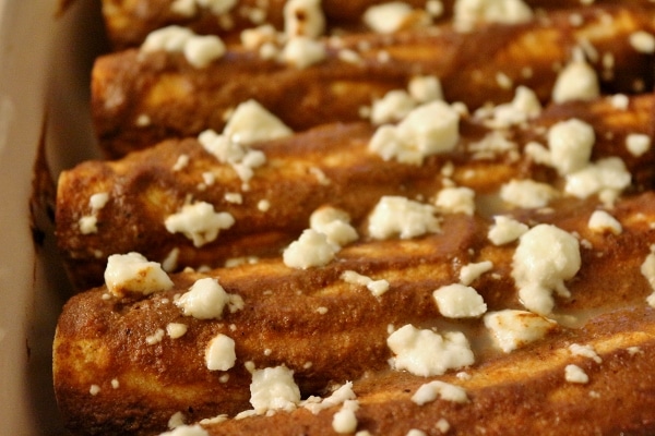 a closeup of baked enmoladas with crumbled cheese on top