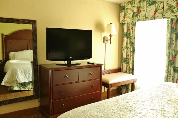 A hotel bedroom with a dresser and a television