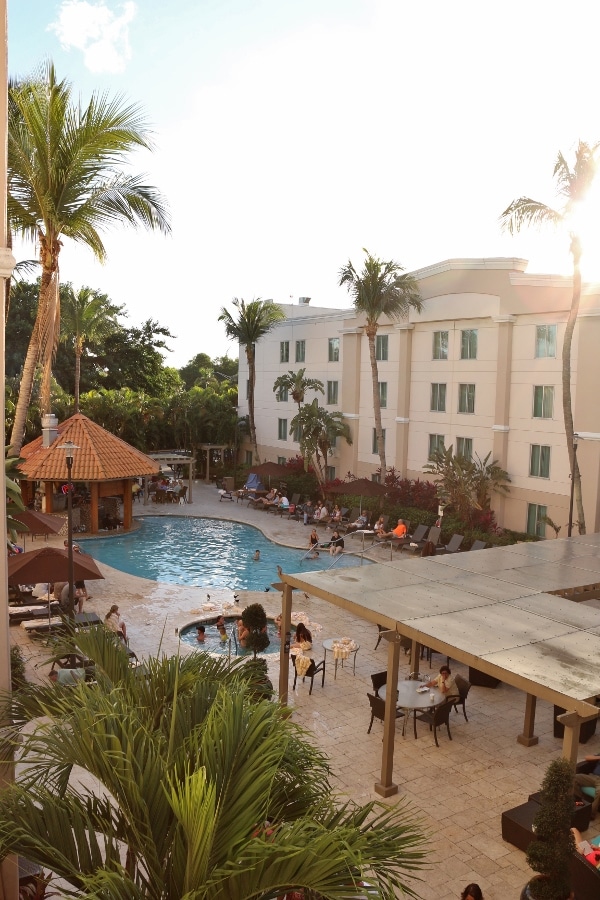 view of a hotel swimming pool with people sitting in chairs and at tables around it