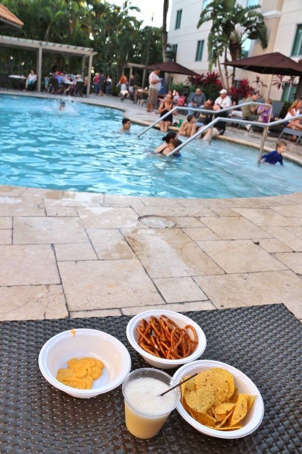 plates of snacks and a drink on a table next to a hotel pool