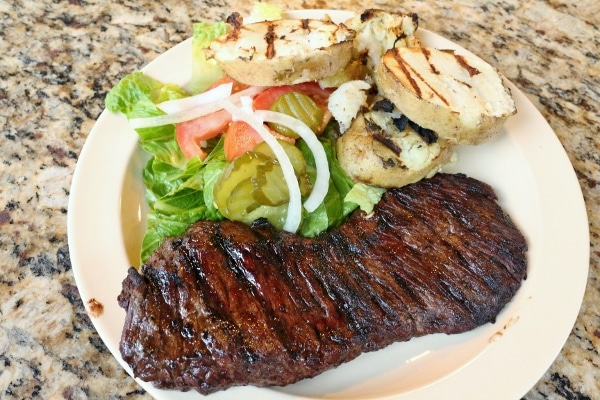 steak served with grilled potatoes and salad on a plate