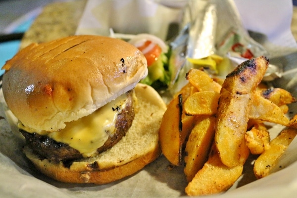 A cheeseburger with potato wedges served on a plate