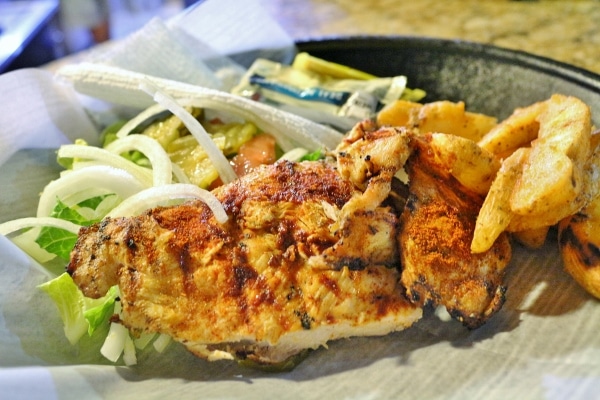 grilled chicken with potatoes wedges and salad on a plate