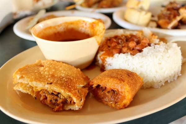 A plate of rice with stewed beans, and pieces of fried foods
