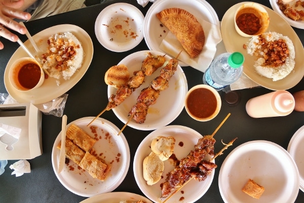 overhead view of skewered meats and fried empanadas on a table