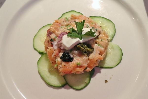 A plate of salmon tartare served over cucumber slices