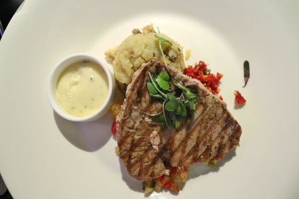 a grilled tuna steak with mashed potatoes and sauce on the side