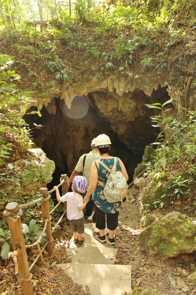 A group of people in hardhats climbing into a dark cave