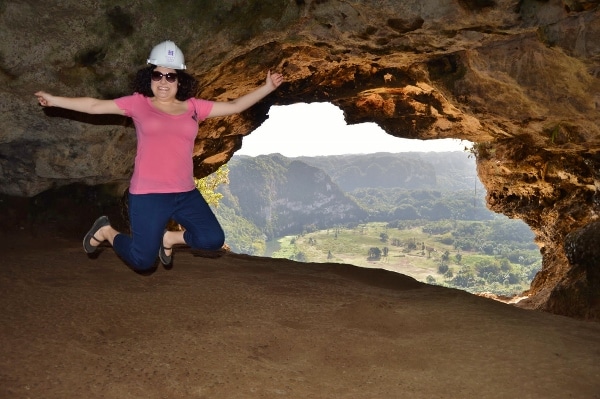 A person jumping in front of nice view from a cave