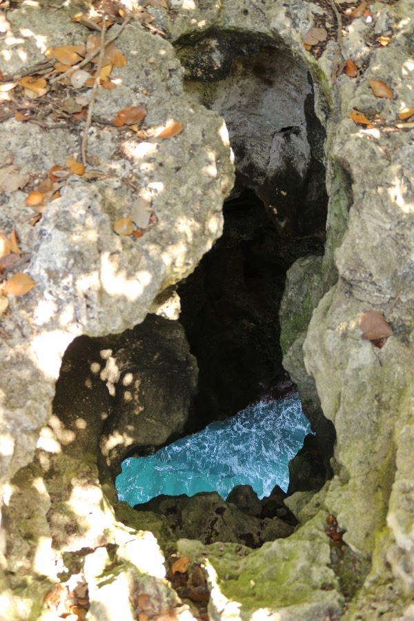 A close up of an opening in a rock looking down at the water below