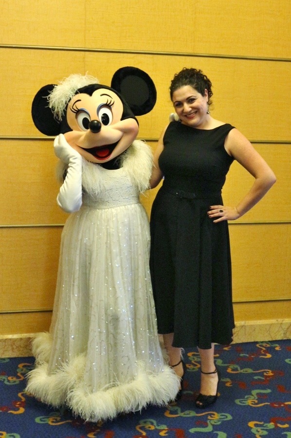 A woman in a black dress posing with Minnie Mouse in a ball gown