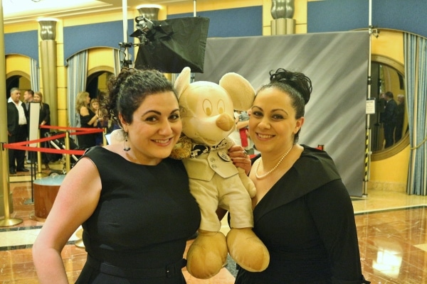 two women posing with a gold Mickey Mouse plush