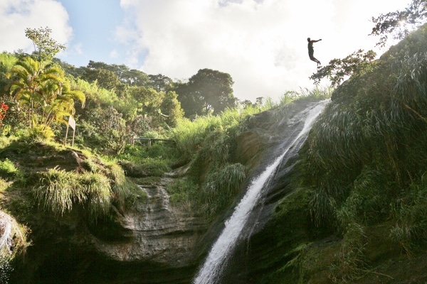 a man jumping from the top of a waterfall