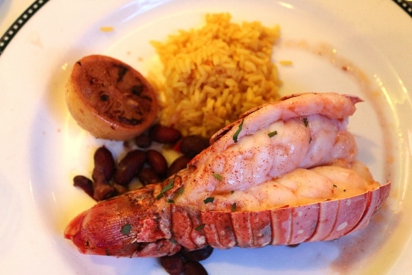 a lobster tail with rice served on a white plate