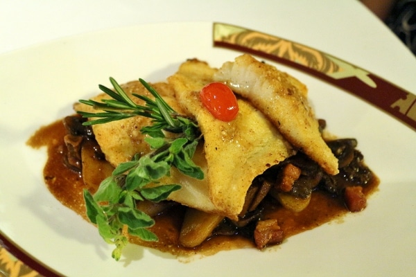 A plate of fish served over vegetables