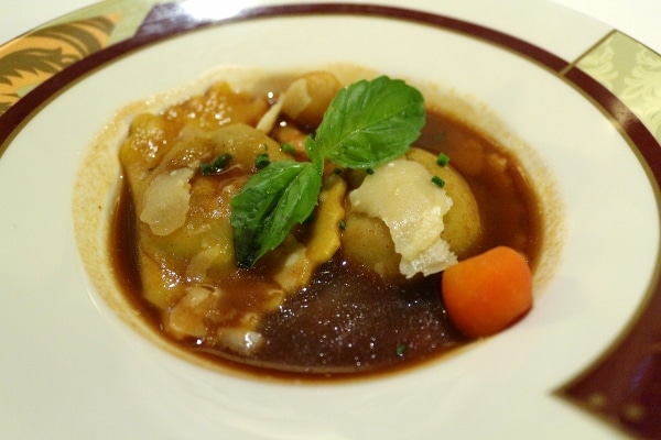 a small plate of ravioli in a dark brown sauce