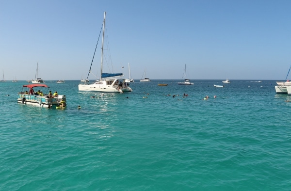 a view of boats and swimmers in tropical water