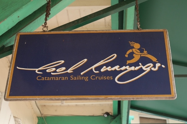 A close up of a sign that says Cool Runnings Catamaran Sailing Cruises