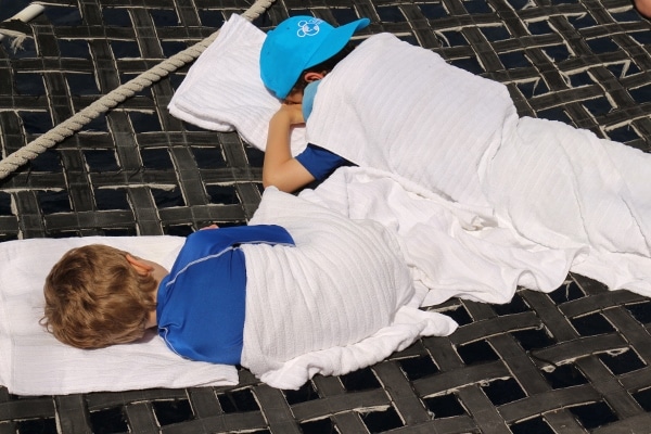 two kids covered with towels napping on a catamaran